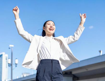 青空の下伸びをするビジネス女性・就活生 青空の下伸びをするビジネス女性・就活生の写真