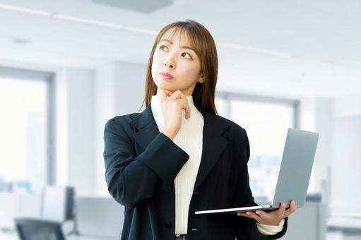 パソコンを持って考える女性ビジネスマン 女性,パソコン,考えるの写真素材