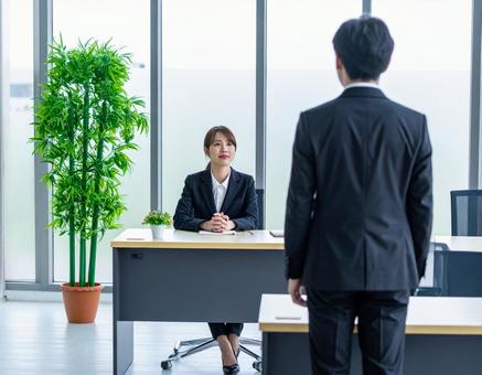 女性上司とその前に立つサラリーマンの部下の写真