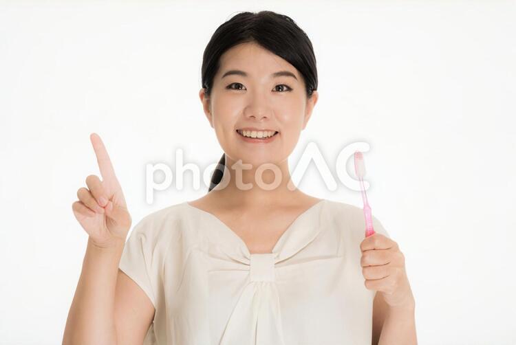 歯ブラシを持ち人差し指をたてる笑顔の女性 女性,歯ブラシ,指さしの写真素材