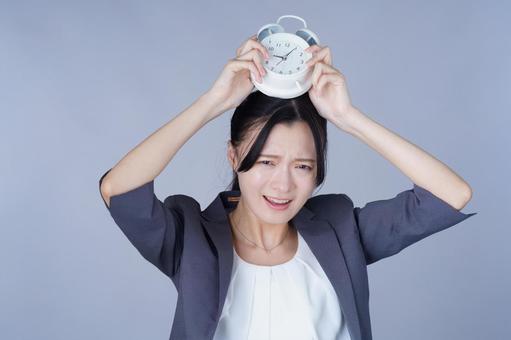 時計を頭上にかかげたスーツを着た女性 女性,目覚まし,持つの写真素材