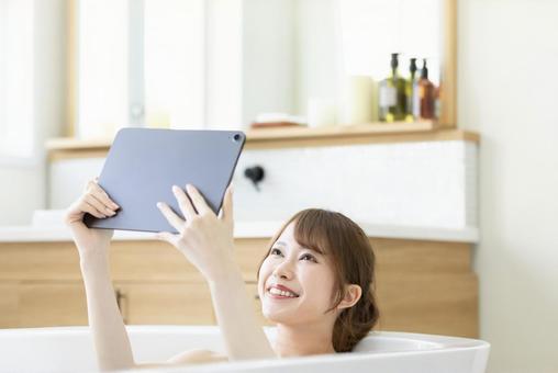 お風呂に浸かりながら動画を楽しむ女性 お風呂に浸かりながら動画を楽しむ女性 女性,人物,タブレットの写真素材