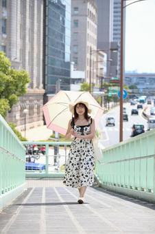 日傘をさして歩道橋のスロープを昇る女性 日傘をさして歩道橋のスロープを昇る女性の写真