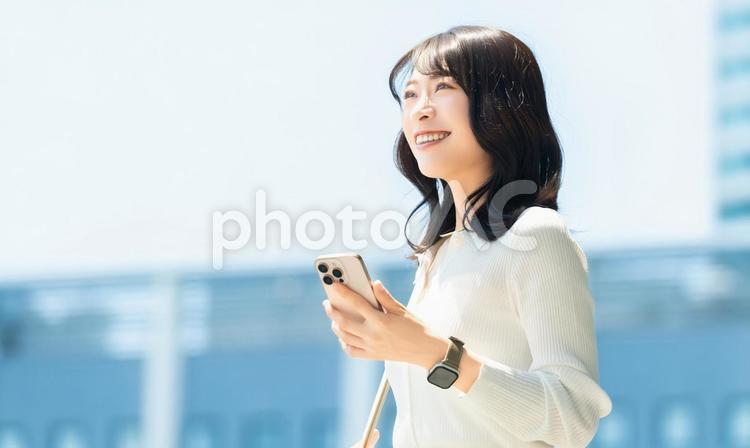 屋外でスマホを持つ女性・ビジネスウーマン 女性,スマホ,スマートフォンの写真素材