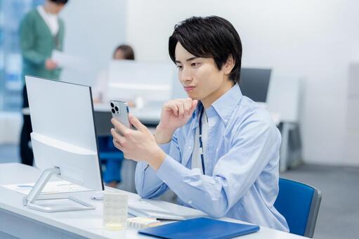 オフィスでスマホを使うビジネスマン スマホ,ビジネスマン,笑顔の写真素材