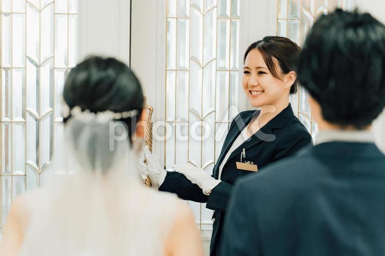 結婚式場のドアを開けるスタッフの女性 ウェディングプランナー,ドアスタッフ,入場の写真素材