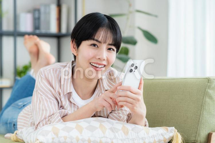 リビングでスマホを使う若い女性 リビングでスマホを使う若い女性 スマホ,女性,若いの写真素材