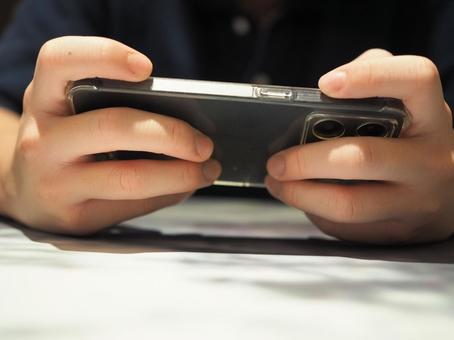 The hand of a young man holding a smartphone sideways, JPG