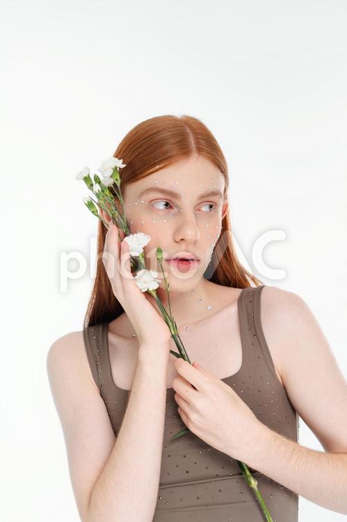 白いカーネーションを顔につけ持つ女性 女性,カーネーション,横目の写真素材