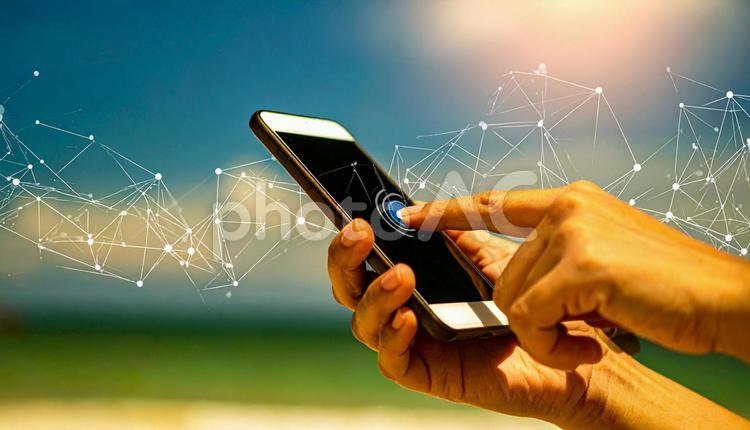 スマートフォンを操作する手　青空背景 スマートフォン,メール,ラインの写真素材
