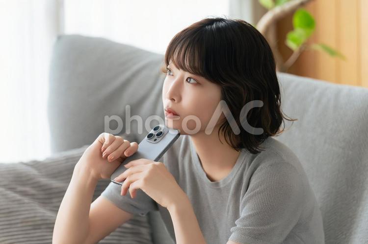 スマホを持って考えごとをする女性 女性,スマホ,スマートフォンの写真素材