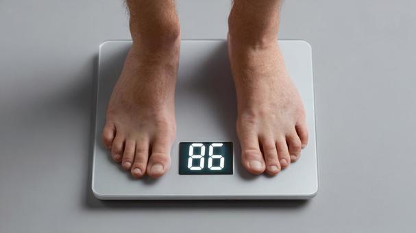 体重計に乗った男性の足元の写真