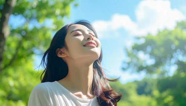 緑の中で目を閉じて深呼吸する日本人女性 緑の中で目を閉じて深呼吸する日本人女性の写真