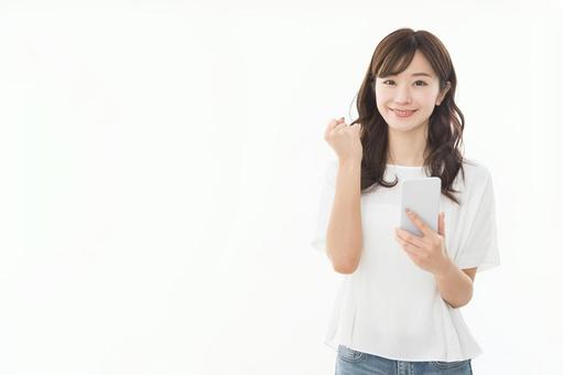 若い女性 スマートフォン ガッツポーズ 若い女性 スマートフォン ガッツポーズの写真