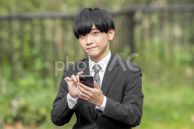 屋外でスマホを使うビジネスマン 就職,キャリア,若いの写真素材