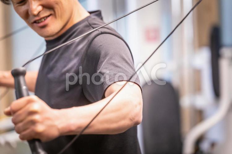 スポーツジムでケーブルマシンを使う男性 ケーブルマシン,ケーブル,ワークアウトの写真素材