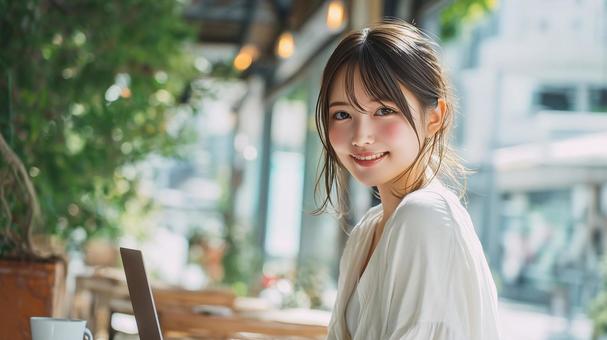 緑豊かなカフェでノートPCを使用する女性 緑豊かなカフェでノートPCを使用する女性の写真