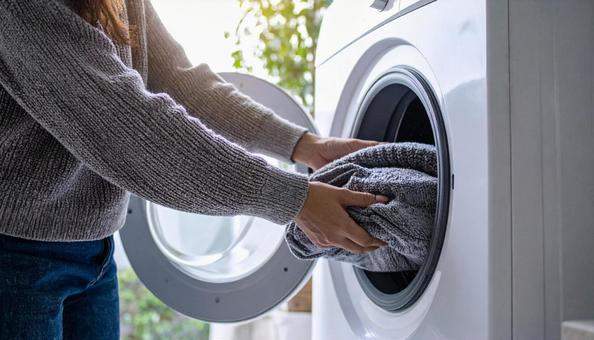 洗濯機から洗濯物を取り出す女性の手 洗濯機から洗濯物を取り出す女性の手の写真