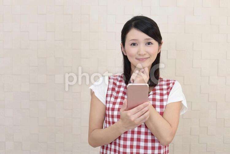 スマートフォンを持つ笑顔の女性 女性,主婦,女の写真素材