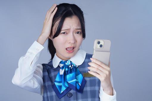 青いリボンの制服の女性がスマホ見る 女性,スマートフォン,持つの写真素材
