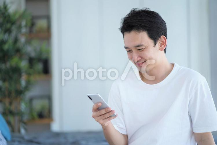 寝室で携帯を見る男性 男性,ビジネスマン,テレワークの写真素材