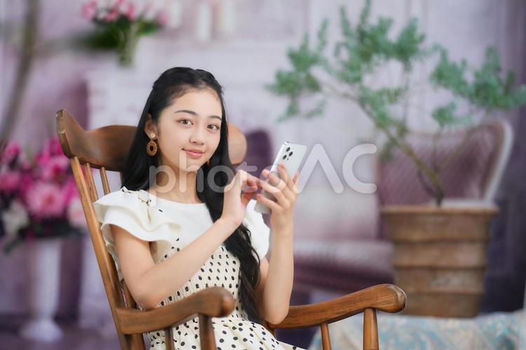 椅子に座りスマホを持ちカメラ目線の女性 女性,スマホ,持つの写真素材