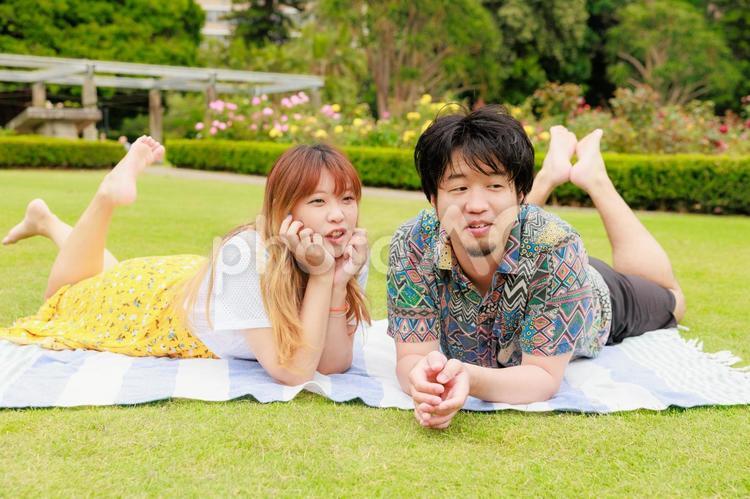 芝生の上に転がる仲の良い男女	 ピクニック,人物,日本人の写真素材