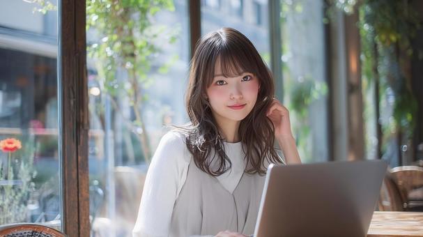 緑豊かなカフェでノートPCを使用する女性 緑豊かなカフェでノートPCを使用する女性の写真