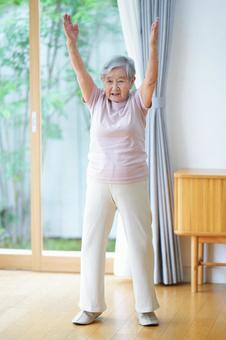 両腕を上に伸ばす高齢女性の写真
