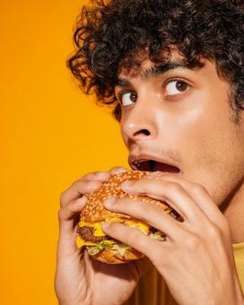 視線が印象的なハンバーガーを食べる男性 視線が印象的なハンバーガーを食べる男性の写真