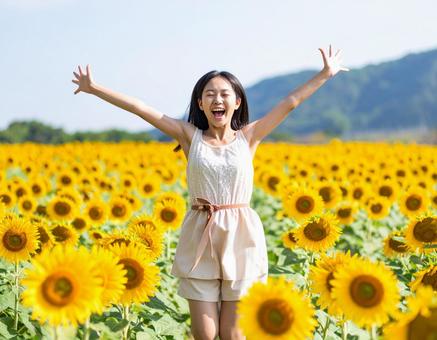 満開のひまわり畑で喜びを表現する少女 満開のひまわり畑で喜びを表現する少女の写真