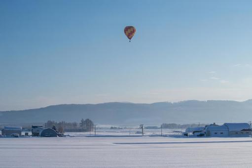 極寒の冬空を静かに漂う熱気球 丘,熱気球,雪原の写真素材