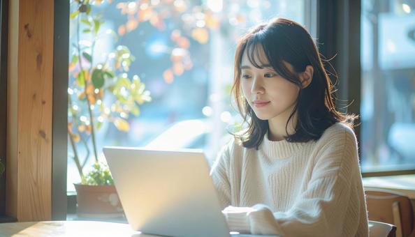 カフェでノートパソコンを使う日本人女性 カフェでノートパソコンを使う日本人女性の写真