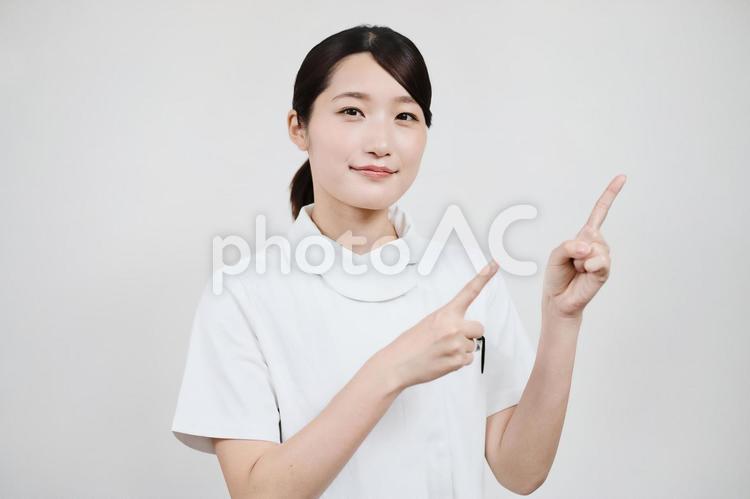 指さしのポーズをする白衣の女性  看護師,ナース,女性の写真素材