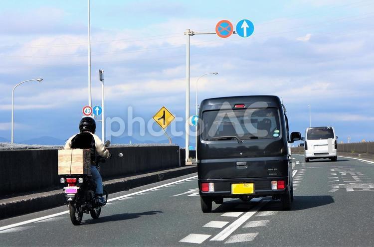 荷物を積んで走行中のバイクを追い越し オートバイ,追い越し,追い抜くの写真素材