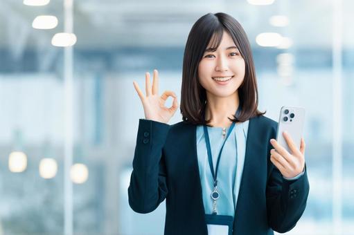 スマホを持ってOKポーズをする笑顔の女性 スマホを持ってOKポーズをする笑顔の女性 女性,ok,スマホの写真素材