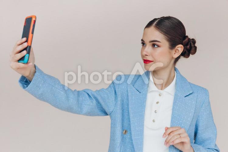 無表情で撮影するスーツの女性 女性,水色,持つの写真素材