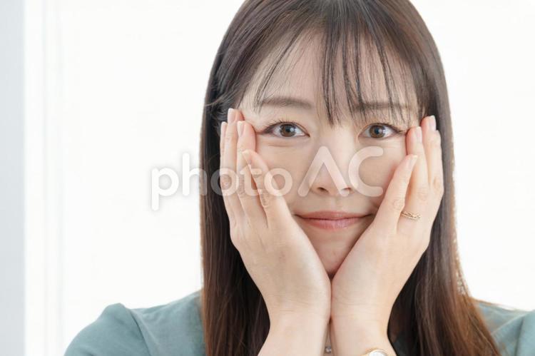 両手に頬を当てる女性 スキンケア,美容,女性の写真素材