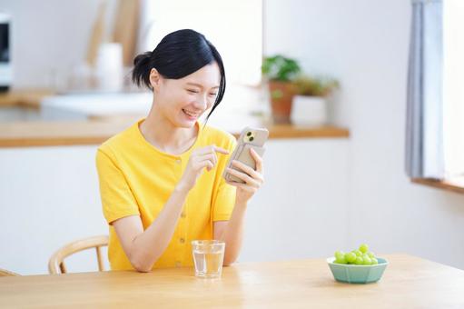 スマホを持ち笑う黄色の服の女性 女性,スマートフォン,持つの写真素材