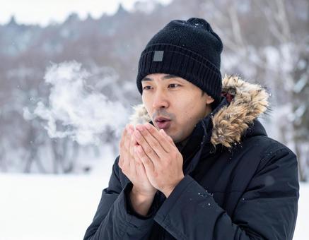 冬に手に息を吹きかける男性 冬に手に息を吹きかける男性の写真