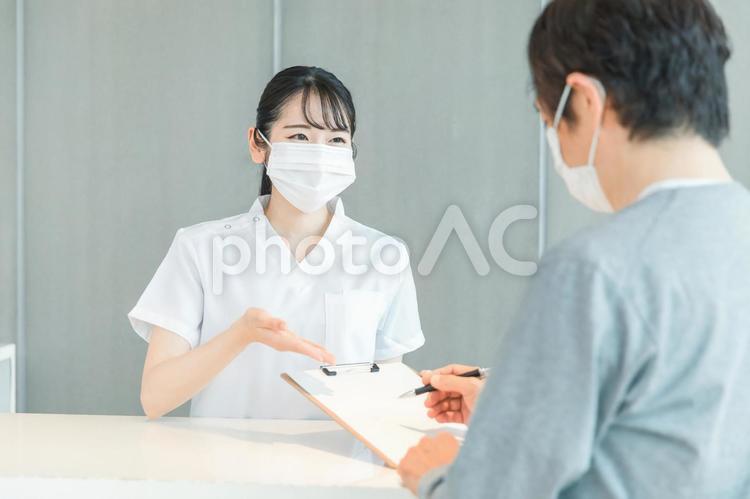 受付にいる看護師と患者（マスク） 医療事務,マスク,受付の写真素材