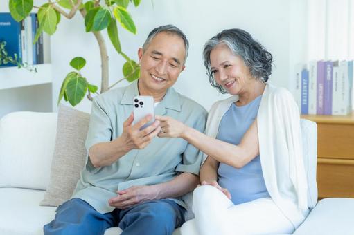 リビングでスマホを見るシニア夫婦 リビングでスマホを見るシニア夫婦 スマホ,シニア,笑顔の写真素材