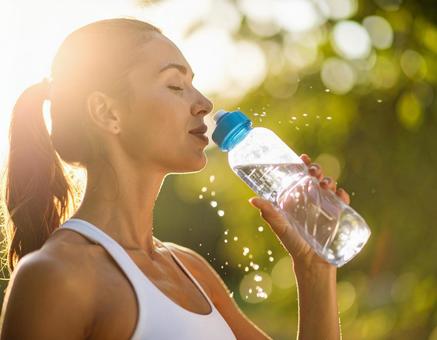 ペットボトルの水を飲むスポーティーな女性 ペットボトルの水を飲むスポーティーな女性の写真