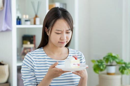 ケーキで悩む若い女性 ケーキで悩む若い女性の写真