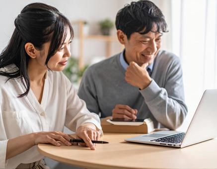 リビングで調べ事をする中年夫婦 リビングで調べ事をする中年夫婦の写真