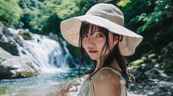 夏の渓流沿いの遊歩道に立つ若い日本人女性 夏の渓流沿いの遊歩道に立つ若い日本人女性の写真