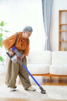 ソファの前のラグを掃除する高齢女性 女性,掃除,掃除機の写真素材