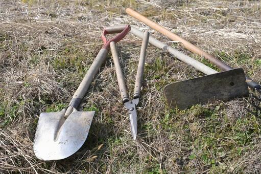  田んぼの畔に並べられた農作業の道具 シャベル,スコップ,剪定ばさみの写真素材