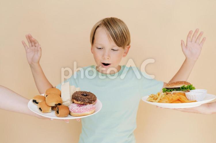 ドーナツとハンバーガーを見て驚く男の子 男の子,人物,軽食の写真素材