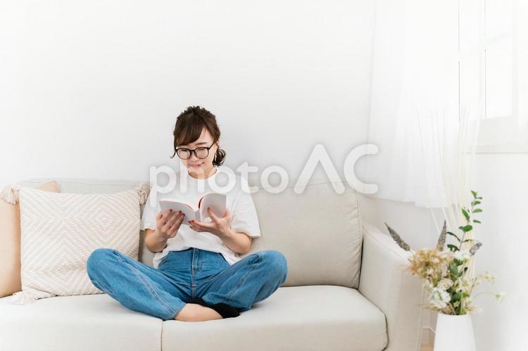 家のソファで読書するおしゃれな日本人女性 読書,本,読むの写真素材